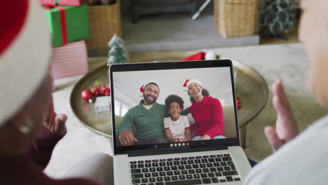 Diversas-Amigas-Mayores-Usando-Una-Computadora-Portátil-Para-Videollamadas-Navideñas-Con-Una-Familia-Feliz-En-La-Pantalla