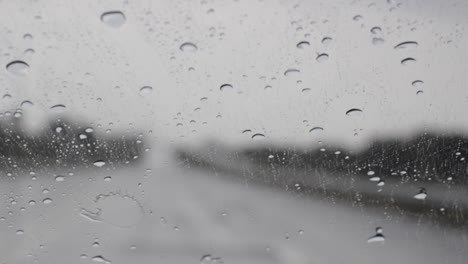 Gotas-De-Lluvia-Que-Caen-Sobre-El-Parabrisas-De-Un-Camión-Y-Obras-De-Limpiaparabrisas,-Vista-Borrosa-De-La-Carretera-En-Un-Ambiente-Oscuro,-Conducción-Bajo-La-Lluvia-Desde-El-Interior,-Imágenes-De-Mano-En-Cámara-Lenta