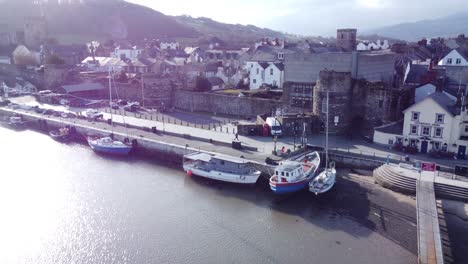 idyllic conwy harbour fishing town boats on coastal waterfront aerial push in