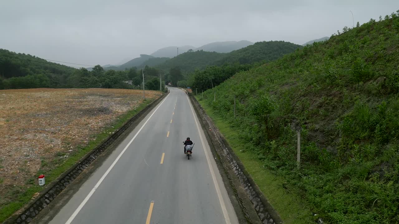 Motorcyclist on a Country Road Through Lush Mountains