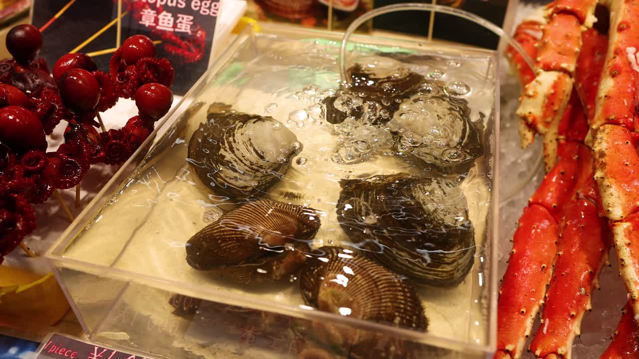 Close-up shot of king crab legs and live clams in water at a Japanese market