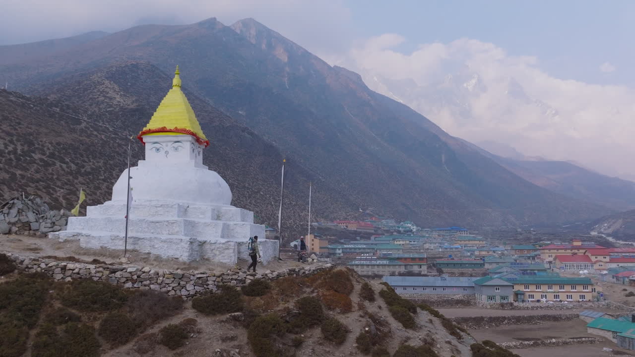 Drone view of locals circling Buddhist Stupa at Dingboche for religious rituals, scenic village and hill landscape on Everest Base Camp trek in Nepal, sherpa community, serene view of cloudy weather