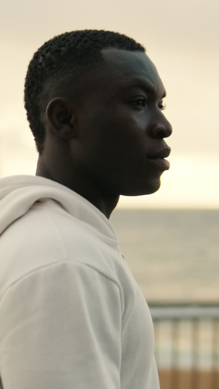 Profile of Young Black Man in White Hoodie Looking Out at the Ocean
