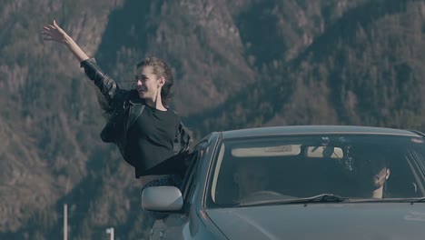 young woman in jacket sits on car window and enjoys view