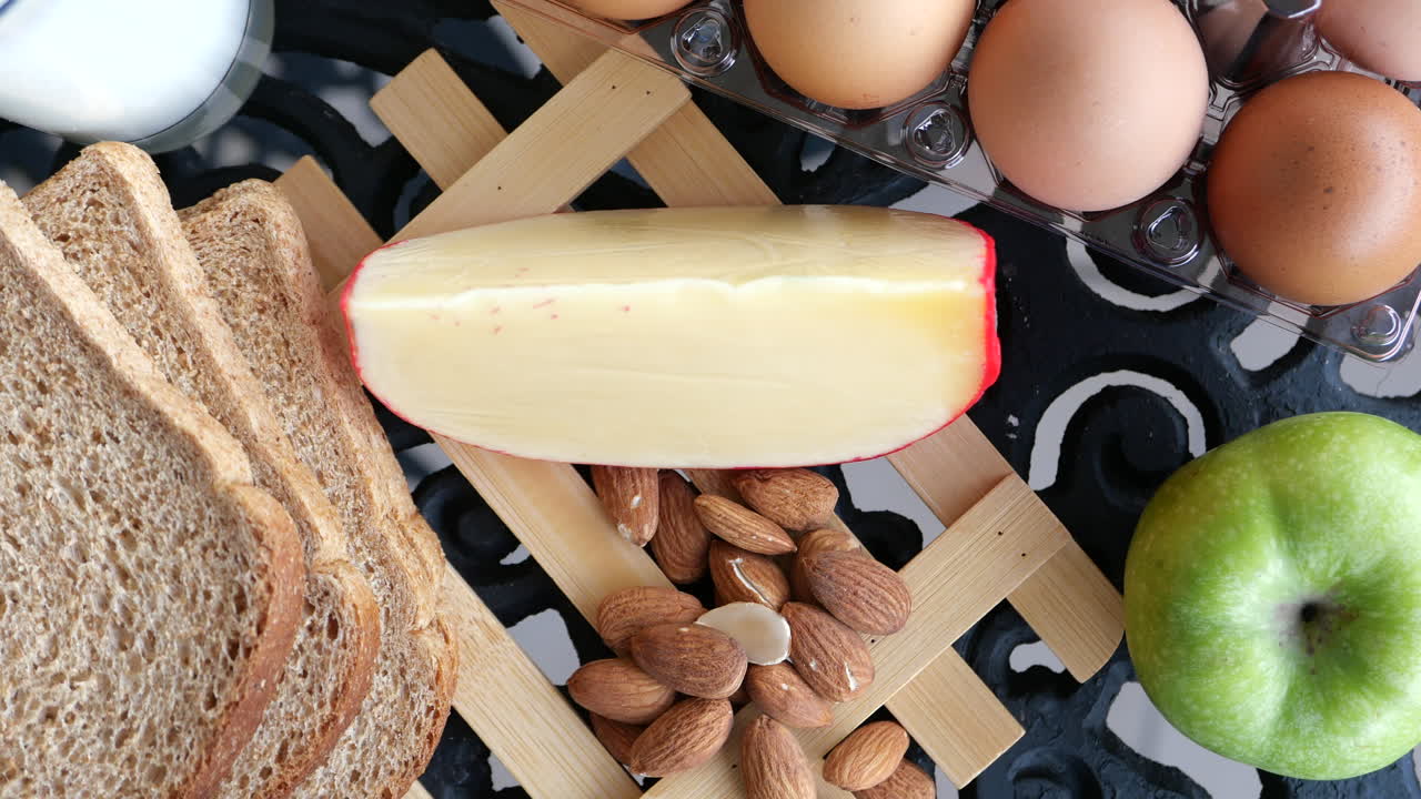 Sund morgenmad med æg, brød, ost, mandler og æble
