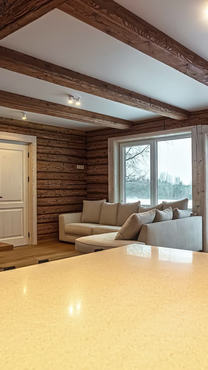 Beautiful interior design of a modern yet rustic log cabin in Latvia, featuring exposed wooden beams, a cozy living room, and a view of a winter landscape - A trucking reveal vertical shot