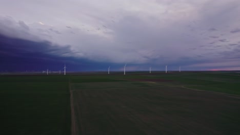 Turbinas-Eólicas-En-Un-Vasto-Campo-Verde-Bajo-Un-Espectacular-Cielo-Tormentoso-Al-Atardecer