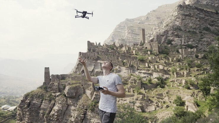 Pilota di drone sopra antiche rovine in un paesaggio montuoso