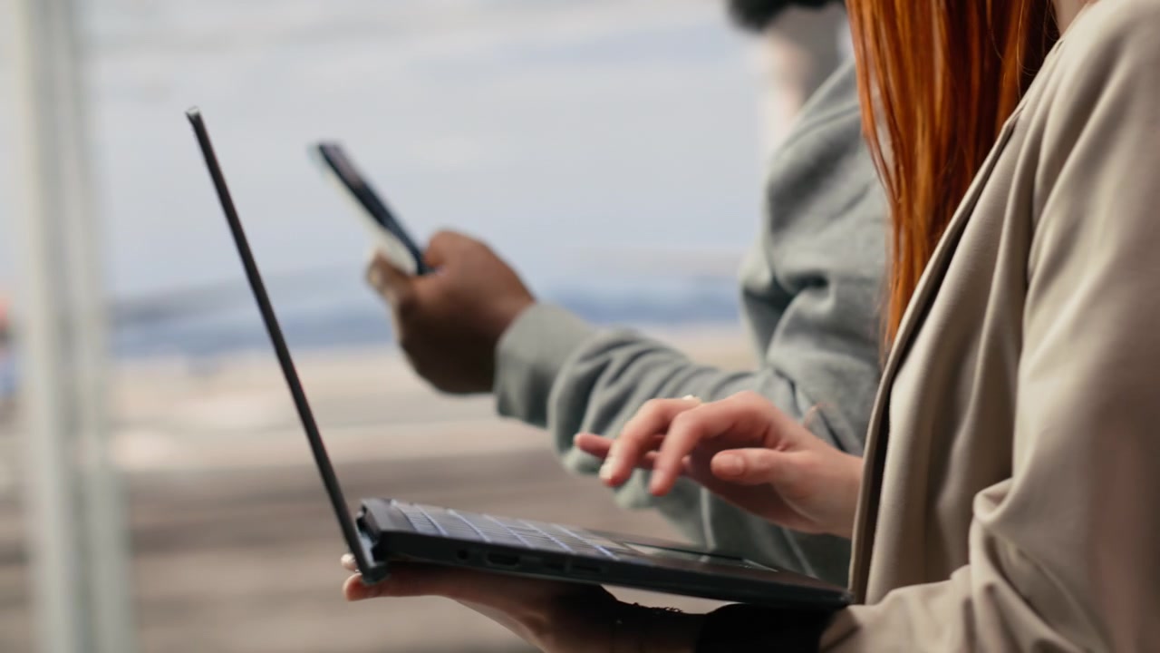 Close up of passengers walking in airport hub, using laptop device