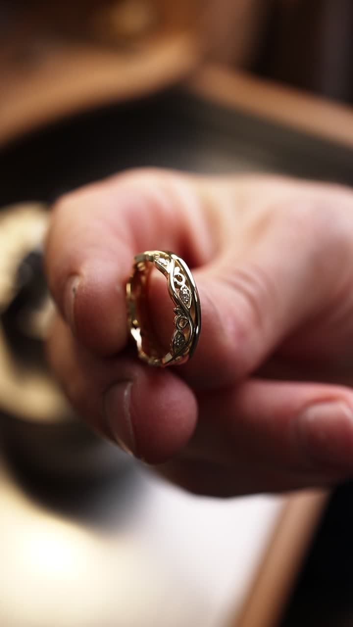 Primo piano di una mano che regge un elegante anello d'oro con diamante.
