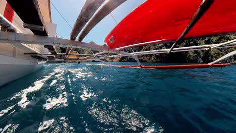 Breathtaking-water-level-view-during-a-traditional-Filipino-boat-ride-off-the-coast-of-Coron,-featuring-crystal-clear-blue-waters