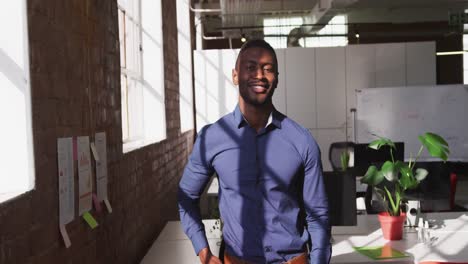 Retrato-De-Un-Hombre-De-Negocios-Afroamericano-Elegantemente-Vestido-En-La-Oficina-Mirando-A-La-Cámara-Sonriendo