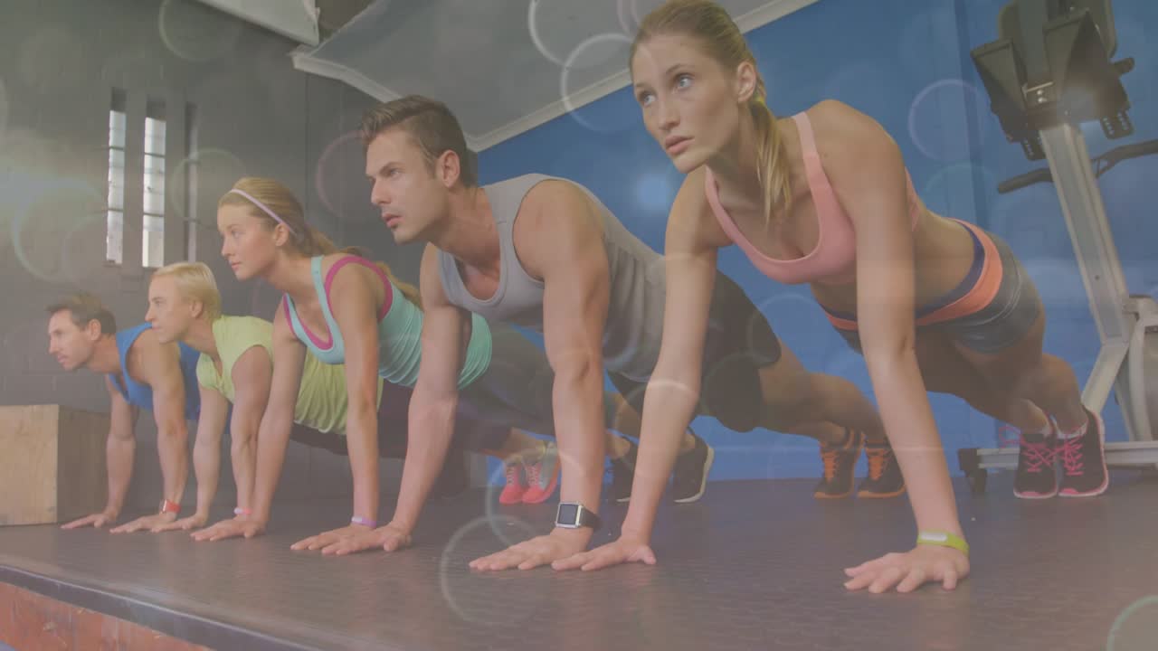 5 aprendices colocando las manos, extendiendo las piernas y haciendo plancha para mantenerse en forma; el bokeh destaca la pulsera de actividad.