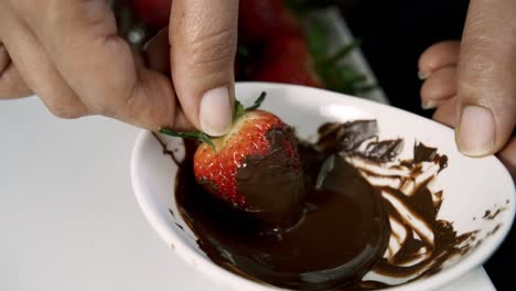 Rolling-strawberries-in-melted-chocolate-in-a-small-white-bowl-vegan-valentines-day-chocolate-beet-muffins