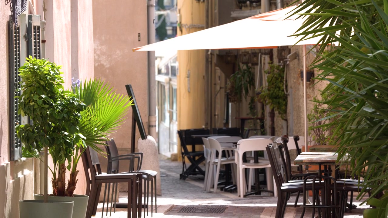 Cena estática de mesas e cadeiras vazias de restaurante em uma rua ensolarada em Cassis