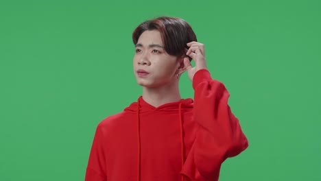 young asian transgender male thinking about something and looking around then raising her index finger and eyes wide open while standing on green screen in the studio