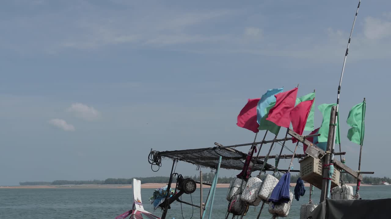 barco de pesca en la playa con banderas ondeando en un día soleado en tailandia, takua pa 4k cámara lenta