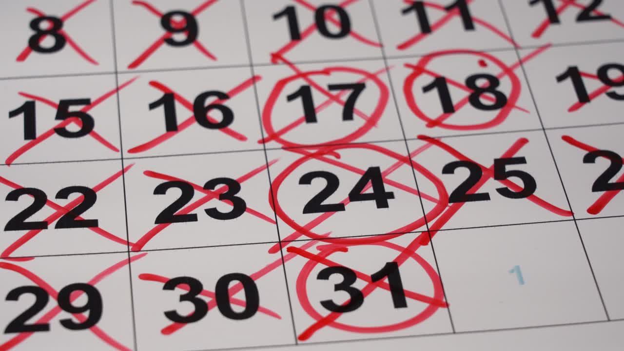 la mano de primer plano dibuja el número de marcador rojo en el calendario.