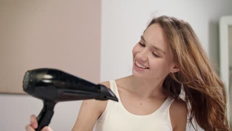 happy woman drying hair in bathroom. portrait of young woman dry hair at morning