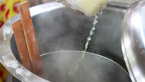 preparing noodles in boiling water at market