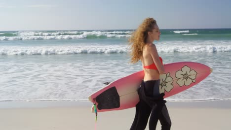 female surfer walking with surfboard at beach 4k