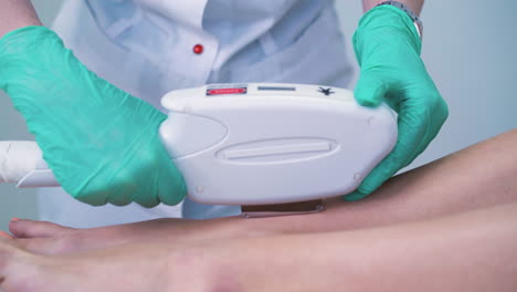 salon cosmetologist in gloves does laser epilation to girl