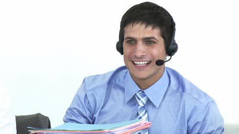 Smiling-businessman-talking-on-a-headset-in-a-call-center