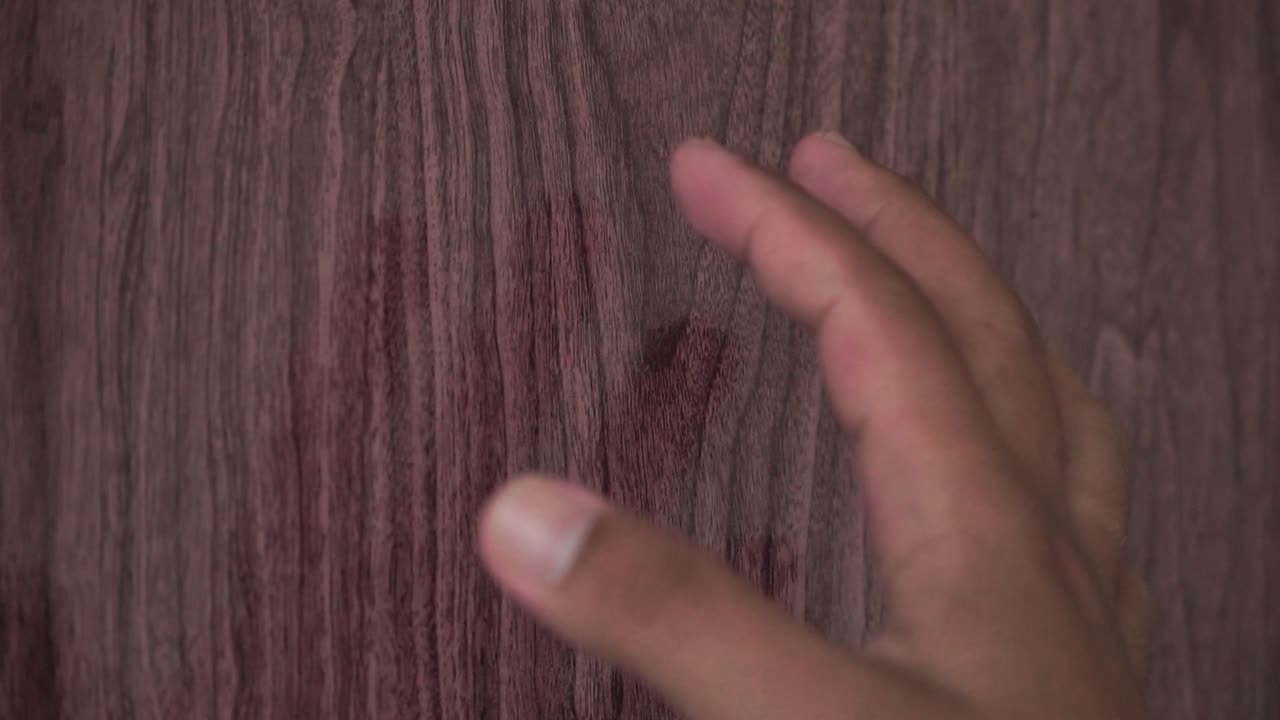A human hand that looks hesitant will knock on the wooden door