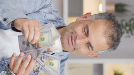 Vertical-video-of-Man-counting-money-looking-at-camera.