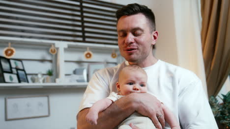 man kissing a newborn baby on the head. father is holding a tiny kid showing him all the love.