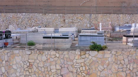 view of a cemetery with numerous gravestones behind a stone wall and fence