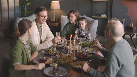 familia multigeneracional feliz brindando entre sí mientras comen juntos en casa