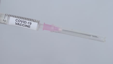 hand with glove removing needle from syringe for covid-19 vaccine - close up