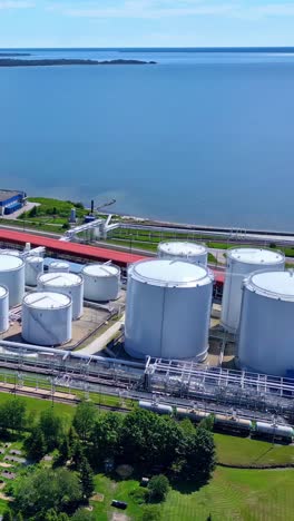 aerial shot showcasing a modern oil or chemical terminal in ventspils, latvia, featuring numerous white storage tanks, pipelines, and a serene waterfront