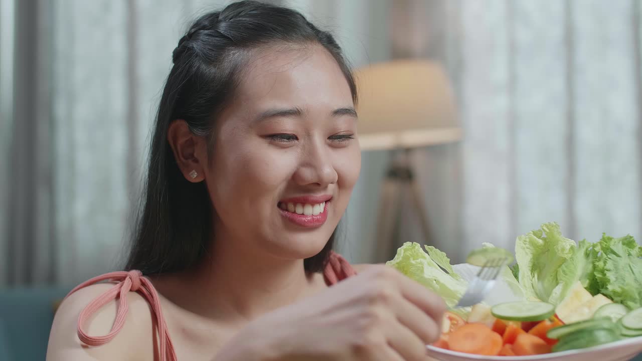 웃는 아시아 여성이 집에서 건강한 음식을 먹는 것을 즐긴다.