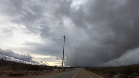 hiperlapso de conducción por molinos de viento con nubes de tormenta en caminos rurales en el desierto de mojave