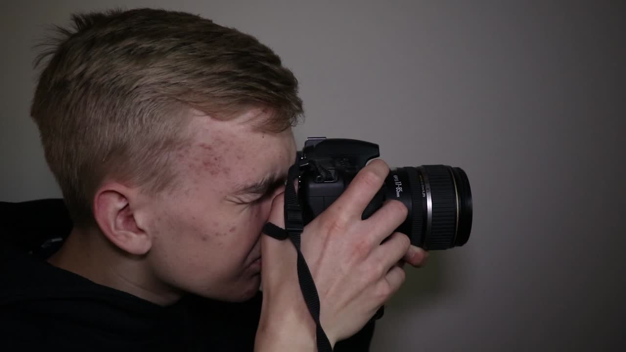 Young guy with DSLR taking pictures on a white background