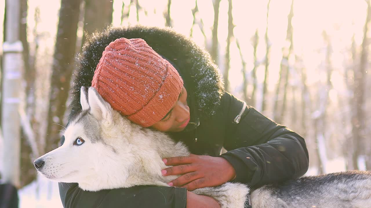 mixed race man hug his dog husky in winter forest park