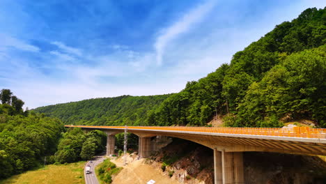 rising along the freeway under construction. cars move by the highway under the constructed road in the mountains