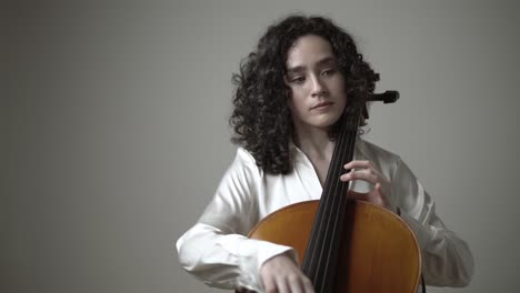 Woman-playing-violin-cello-while-sitting-on-chair