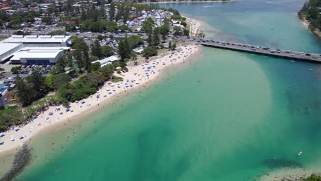 Tallebudgera-Creek-Bridge-Spanning-Across-Blue-Waters-With-People-Enjoying-Sun-And-Sand-At-The-Beach-In-Queensland,-Australia