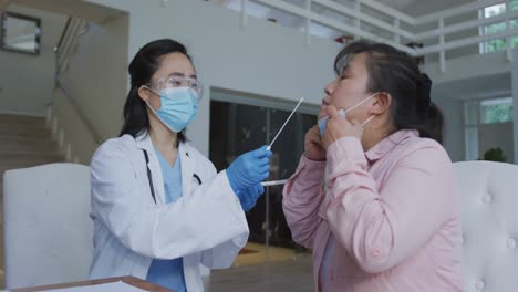 Asian-female-nurse-wearing-face-mask-giving-covid-swab-test-to-female-patient-in-hospital