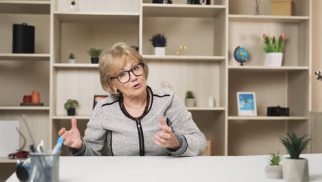 old charismatic woman, a teacher, speaks while looking into the camera, conducting an online conversation