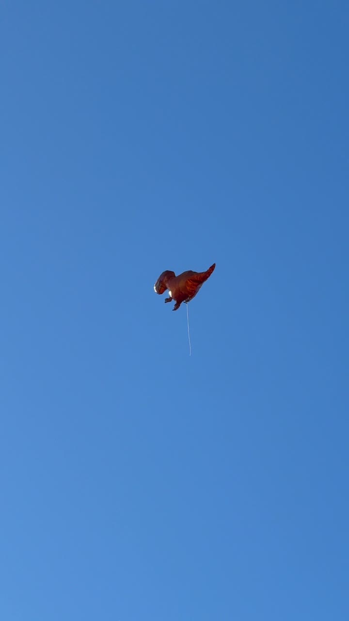 Dinosaur-shaped Kite Flying in a Clear Blue Sky