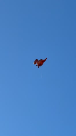 dinosaur-shaped kite flying in a clear blue sky