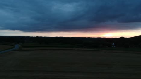 storm clouds and golden sunset over evening agriculture fields, aerial view