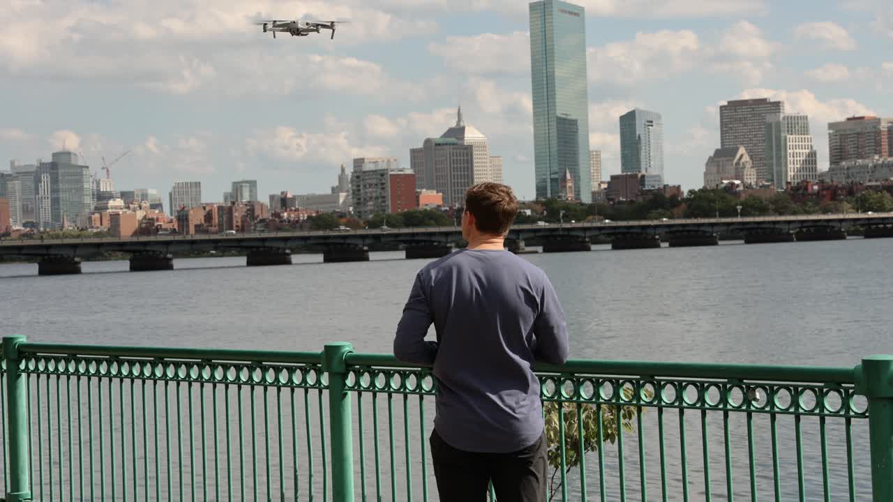 남성 콘텐츠 제작자가 드론을 발사하고 있습니다. 배경에는 보스턴의 스카이라인이 있습니다.