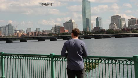 male content creator launching drone, boston skyline in background