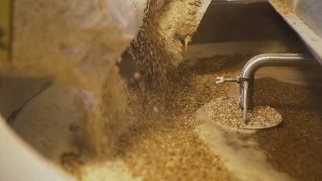 pouring bags of malt into the miller tank - beer making in the brewery - close up slowmo