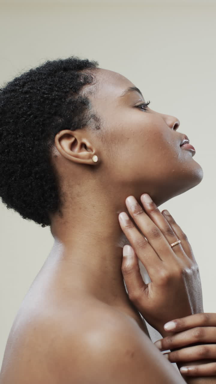Vertical video of african american woman with short dark hair on beige background, slow motion